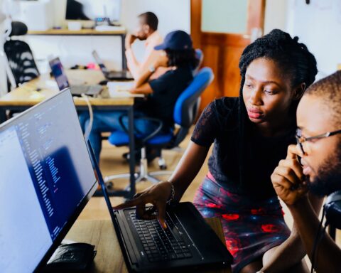 Two young Black people working at a computer. BIPOC