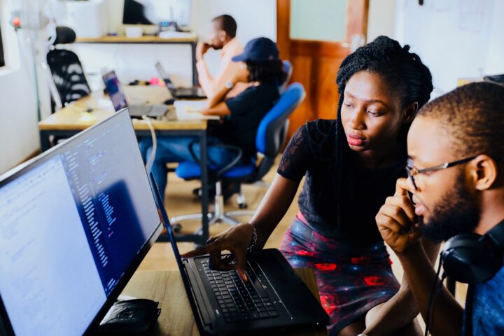 Two young Black people working at a computer. BIPOC