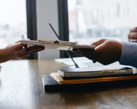 A person handing over a form and providing service to a clerk.