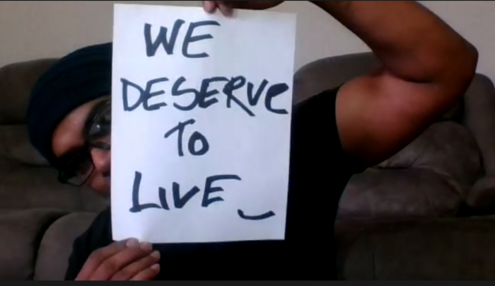 Screenshot of restaurant worker, Md Masud Rana, holding a placard reading "WE DESERVE TO LIVE.", COVID-19, benefits, employment