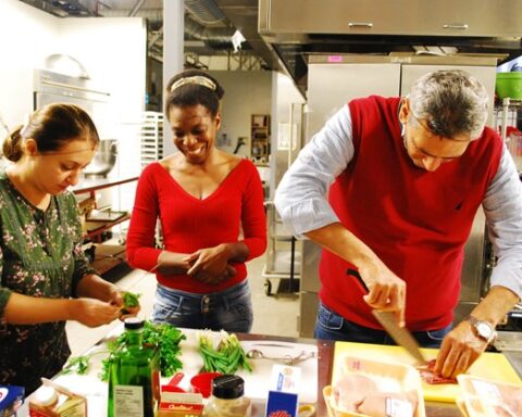 Three people at a table preparing food as part of a program to reduce food insecurity among who are living in transitional housing or experiencing homelessness.