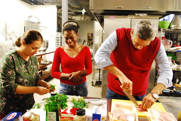 Three people at a table preparing food as part of a program to reduce food insecurity among who are living in transitional housing or experiencing homelessness.