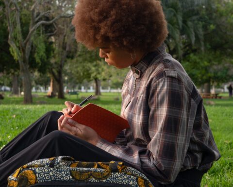 Une jeune fille écrit dans un cahier dans un parc