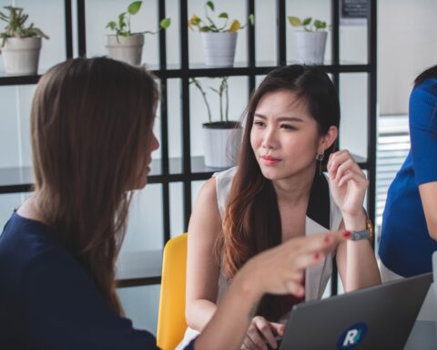 Two women talking in an office space. Microaggressions often happen in everyday life.