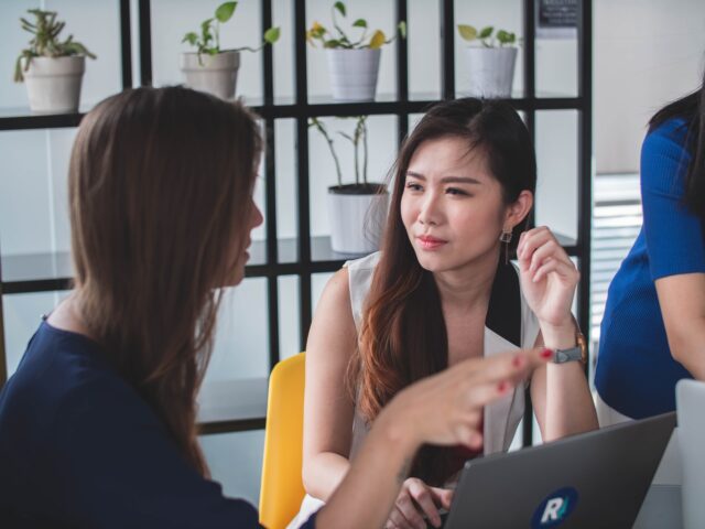 Two women talking in an office space. Microaggressions often happen in everyday life.