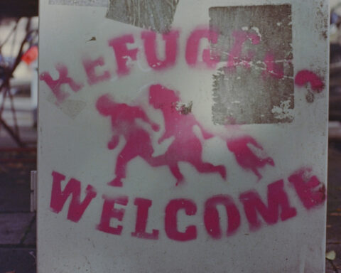 PhPhoto of a sign that reads "Refugees Welcome" and a graphic representation of people running.