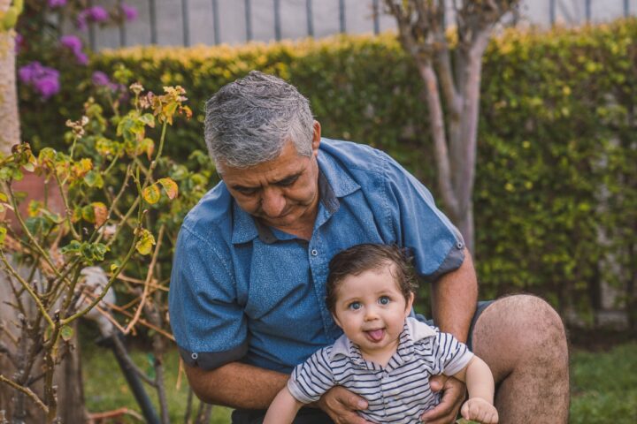 A grandfather holding his grandson in a backyard. Family ties in Canada is often cited by authorities as a reason to deny entry to family members of new Canadians.