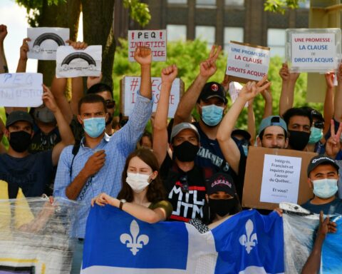 Des manifestants à Montréal soutenant un drapeau du Québec et des pancartes