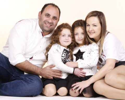 Une famille composé du père, de la mère et de deux enfants pose devant le caméra
