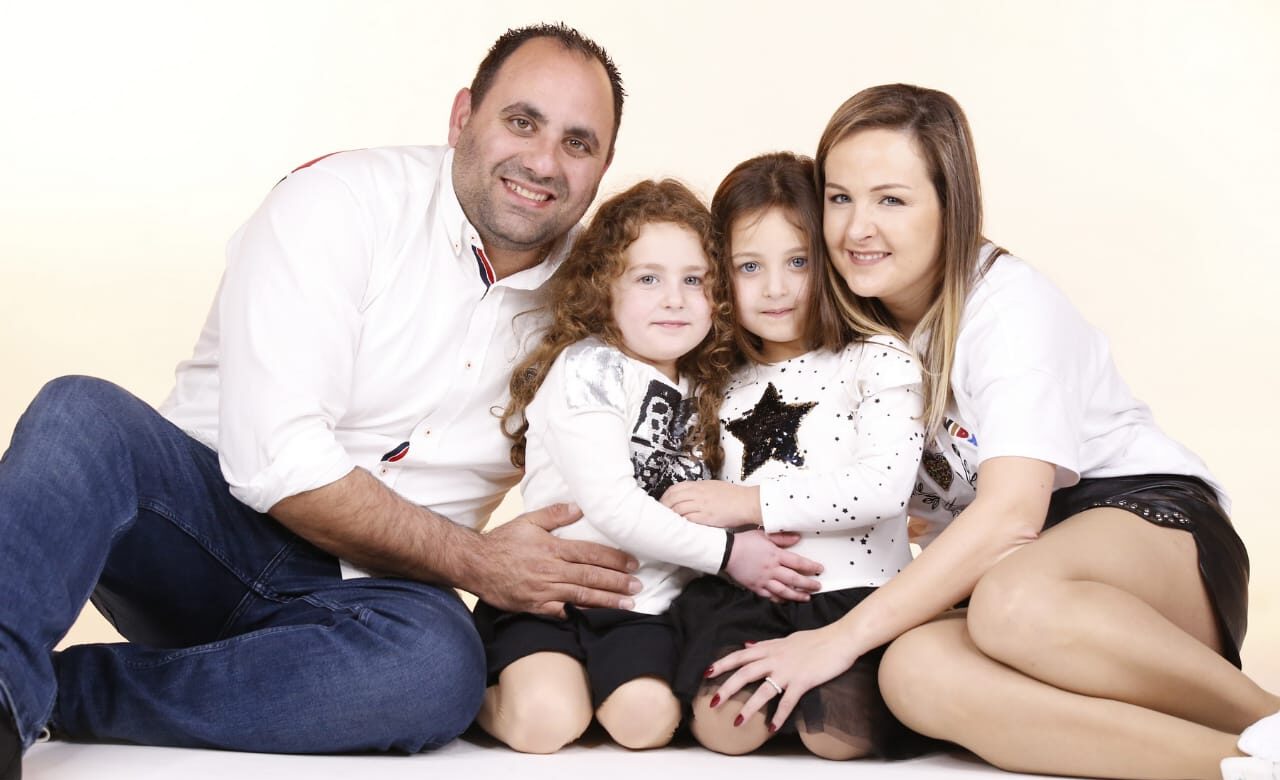 Une famille composé du père, de la mère et de deux enfants pose devant le caméra