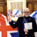 Canadian artist, Owen Grant Innes pictured at dual citizenship ceremony with Queen Elizabeth II's framed picture in the background
