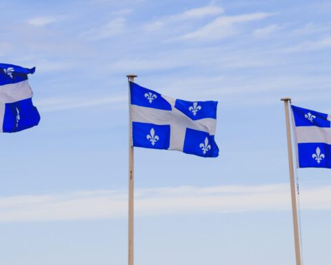trois drapeaux du québec flottant au vent