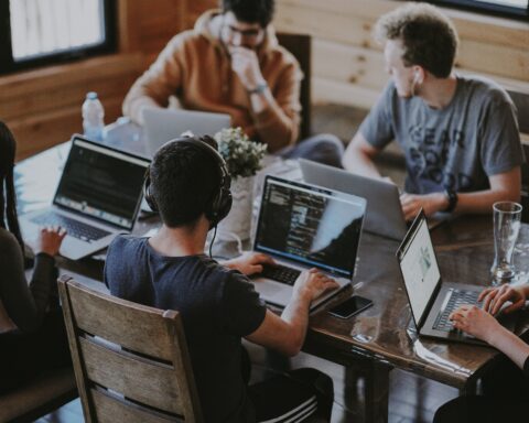 tech and digital workers sit around a table with computers