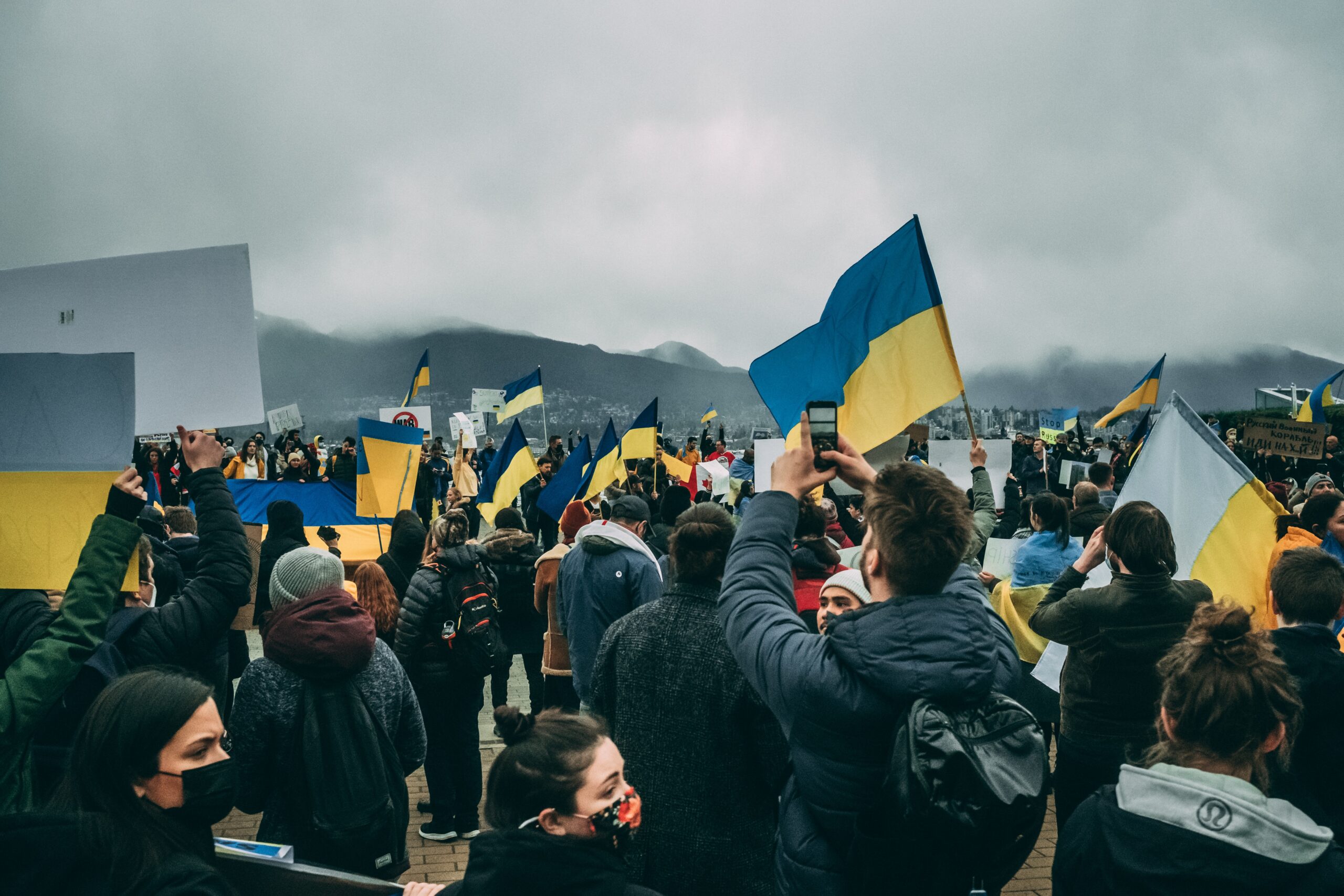 A crowd of people standing with Ukrainian flags and signs at a protest for Ukraine in Vancouver, B.C.