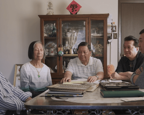 The Chow family and director Weiye Su seated around a dining table covered in photo albums.