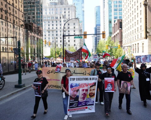 Protesters march in Vancouver on May 20 holding signs that condemn unlawful executions in Iran