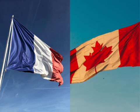 Photo d'un drapeau francais et un drapeau canadien contre le ciel