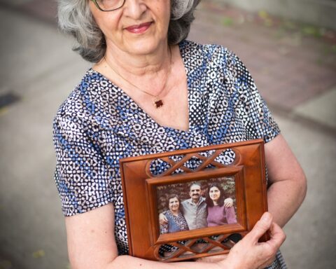 Nahid Mazloum, holds up a portrait of her mother Ezzat Janami Eshraghi, sister, Roya Eshraghi and her father, Enayatollah Eshraghi all of whom were executed in June 1983 in Iran for their belief in the Baha’i faith