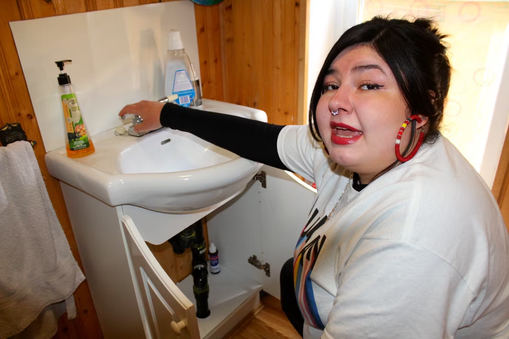 Carolann Battiste turns on the water in her former rental unit in Sydney in May, to show the Cape Breton Post how water leaks from the drain pipe. (Nicole Sullivan / Cape Breton Post)